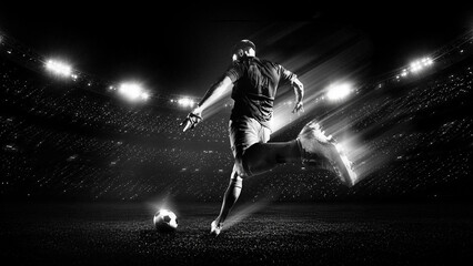Obraz premium Soccer player running to ball under bright stadium lights in black and white. Concept of fast counterattack, match pressure, sports branding and cinematic football promotion.