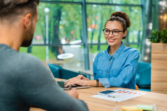 Cropped shot of two colleagues engaged in a conversation while working in a modern office, collaborating and exchanging ideas in a professional workspace.