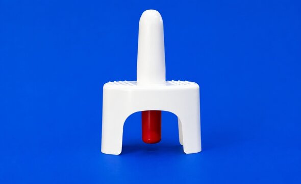 High-resolution close-up of a white and red single-dose nasal spray device isolated on a vibrant blue background, ideal for pharmaceutical and medical concepts.