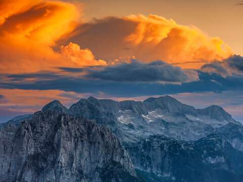 Mountain peaks of Canin group illuminated by sunset clouds in an alpine wilderness represent outdoor adventure and tourism destination, Mangart, Julian Alps, Italy-Slovenia border.