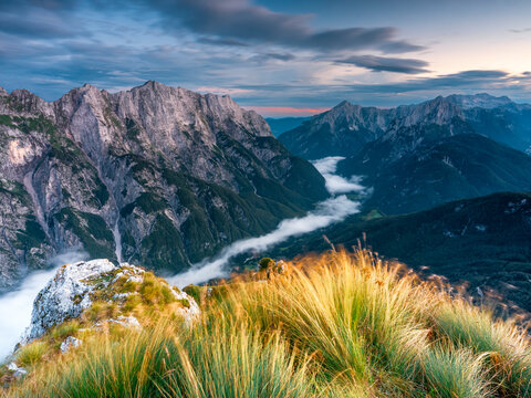 Rugged mountain range with valley fog at twilight provides an inspiring nature tourism destination for outdoor exploration, Mangart, Julian Alps, Italy-Slovenia border.