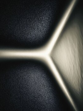 Abstract monochrome close up of textured black leather with bright glowing light highlight at sharp corner minimalist geometric background