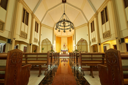 View of the interior of Saint Joseph Catholic Church featuring wooden pews, a central aisle, and a large chandelier in Kecamatan Ambarawa, Jawa Tengah, Indonesia.