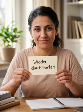 L&auml;chelnde Frau mit mediterraner Heritage h&auml;lt Karte Wieder durchstarten am Schreibtisch &ndash; Weiterbildung Wiedereinstieg Beruf