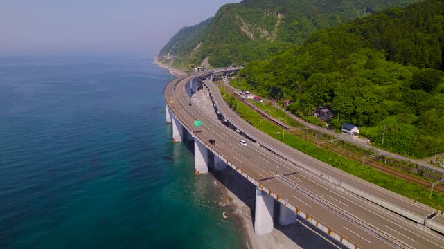 エメラルドグリーンの海上に架かる高速道路 道路と並走して前進するドローン空撮
