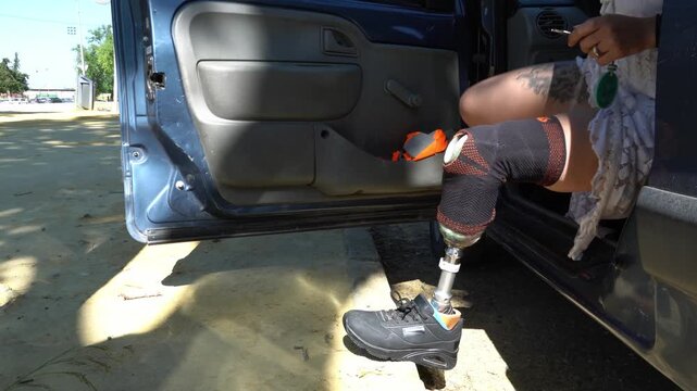 Independent woman with a prosthetic leg getting out of a car. Brave female amputee overcoming challenges and living an active, normal life