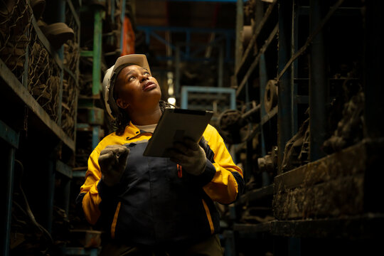 African female engineer checking auto parts inventory with a tablet in warehouse