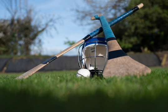 Hurling equipment on grass with helmet, hurleys and sliotar ready for play on outdoor field