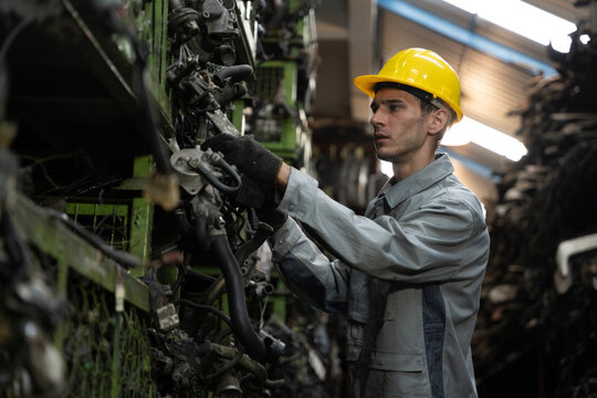 Busy worker inspects parts on shelf in auto junkyard