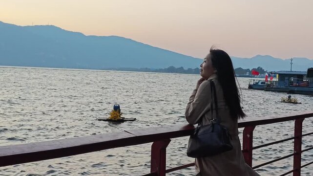 Asian woman tourist watching the sunset over Dianchi Lake at Haihong Wetland Park in Kunming, Yunnan, China