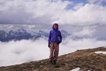 Obraz premium a young tourist in front of snow-covered mountains and clouds. Outdoor travel and an active lifestyle