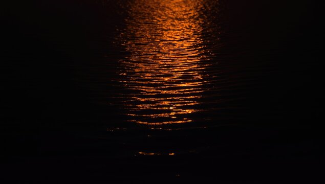 Bright firelight reflected in water set on a deep dark surface