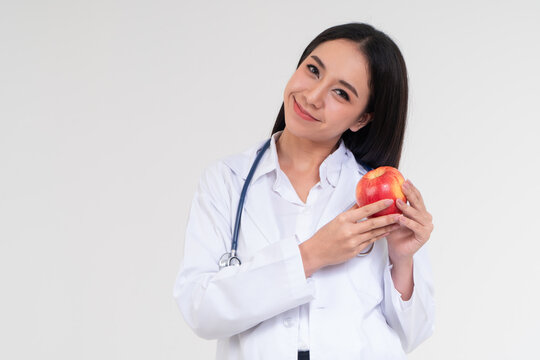 Health and Wellness with a Smile: A radiant healthcare professional offers an apple, symbolizing good health, in a display of caring, conveying wellness.