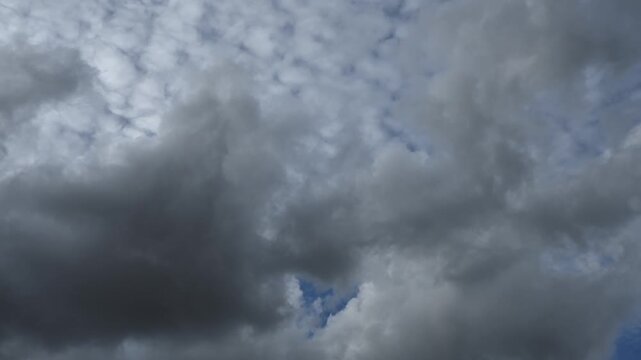 Diffuse white summer clouds move across the blue sky in this time lapse. The sky fills the frame.

