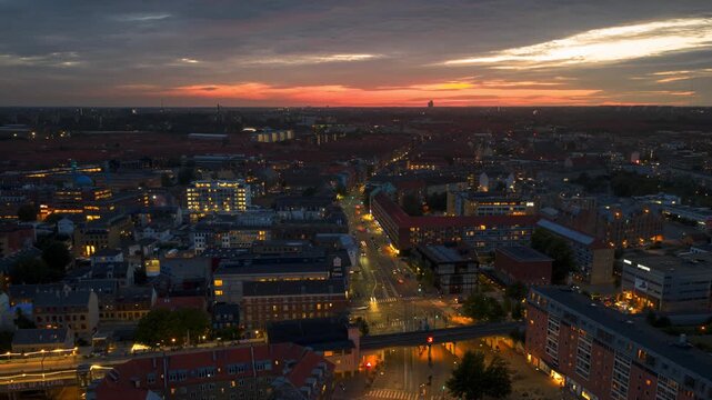 Aerial view of Malmo city skyline at twilight with glowing street lights and dramatic sunset sky.
