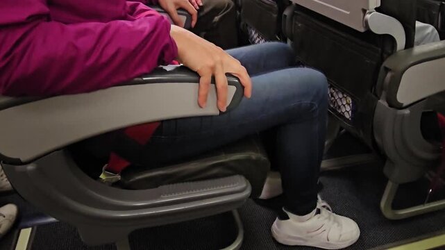 A woman sits on a plane, clutching her seat, afraid of flying. Aerophy and the fear of flying concept