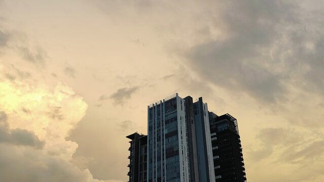 Modern high rise buildings under dramatic cloudy sunset sky in an urban cityscape with warm evening light and architectural skyline view.