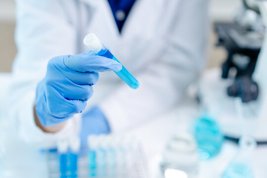 hand of scientist hold test tube with liquid chemical water to recheck experiment result in laboratory, doctor with blue glove research and analyze biochemistry for healthcare and medical innovation