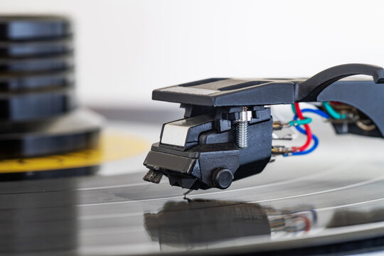 Macro view of phono cartridge and stylus on spinning vinyl record audiophile setup