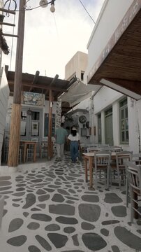 Wander through the picturesque streets of Naxos, Greece, where charming cafes welcome visitors. A diverse couple walking on the streets of Naxos, Greece, during vacation
