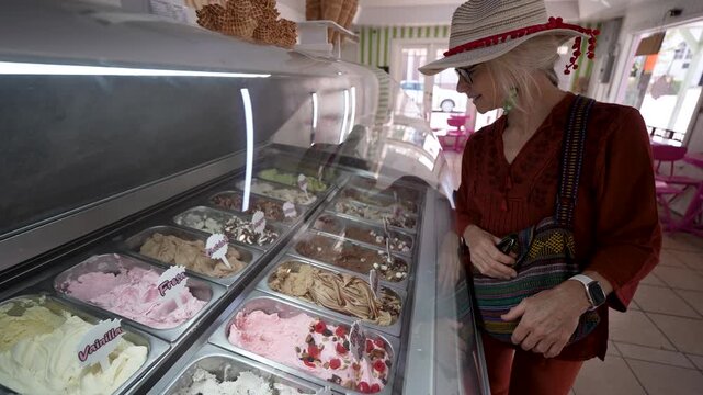 Mature woman picks out her ice cream flavor in a shop while exploring Santa Rosalia in Baja California Sur Mexico on her travel day.