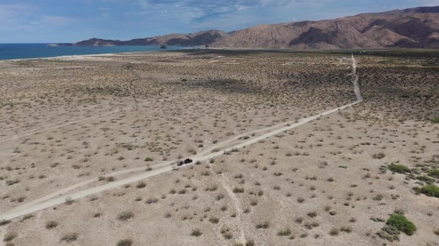 Aerial views show an SUV pulling a teardrop trailer on sandy and dirt roads in Baja California, Mexico, near Gonzaga Bay.