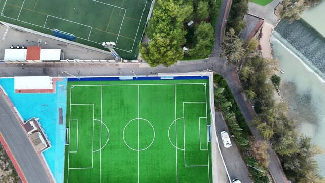Aerial view of two soccer fields in a green park. This footage captures the vibrant turf and surrounding nature. Perfect for sports and recreational themes.
