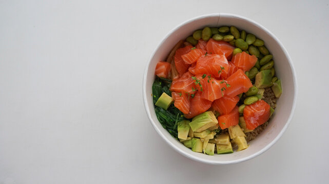 Top view of fresh salmon poke bowl with avocado and edamame on clean white background with large copy space, ideal for healthy eating, wellness, and food branding concepts.