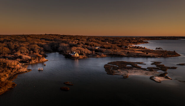 View of Martha's Vineyard coastal landscape with a white house, bare trees and calm waters at sunset Edgartown, Massachusetts, United States.