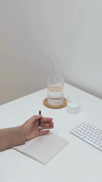 Faceless Woman Writing in Notebook and Typing on Laptop in Modern Workspace