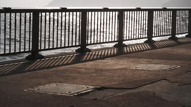 A coastal deck fence with a reflective ocean surface in the background