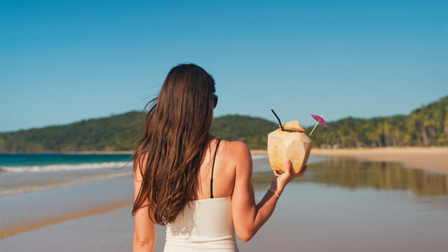 Woman holding coconut drink on tropical philippine beach