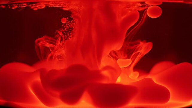 Vibrant red liquid ink swirling and mixing in water with glowing abstract shapes and bubbles