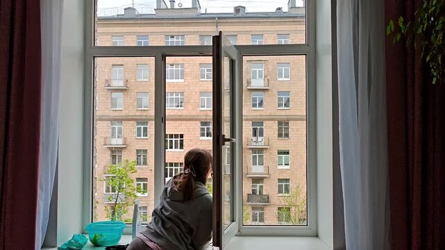 Woman detaching window cleaning robot from glass after automated cleaning cycle. Smart home routine, effortless housekeeping, modern technology convenience.