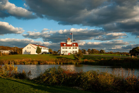 View of the historic Coast Guard Station on Martha's Vineyard with white buildings and red roofs under a dramatic cloudy sky in Edgartown, Massachusetts, United States.