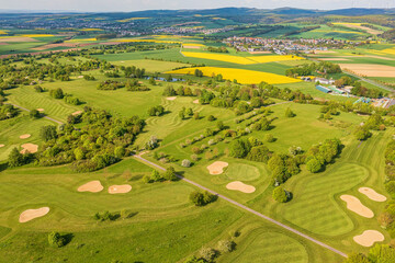 Naklejka premium A bird's-eye view of an idyllic golf course nestled amidst the Taunus forests.