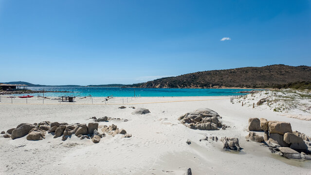 View of Punta Molentis Beach with its white sand, turquoise sea, and granite rock formations under a clear blue sky in Villasimius, Sardinia, Italy.