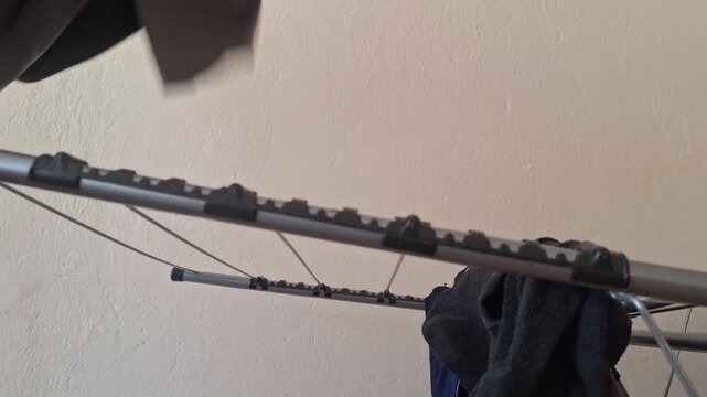 Person adjusts clothing on a drying rack