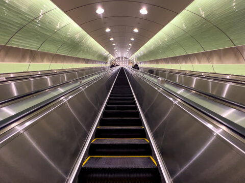 View of the long modern escalators at Grand Central Madison with a green arched ceiling and metallic finishes New York, New York, United States.