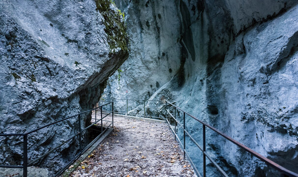 View of the narrow hiking trail through the Gola dell'Infernaccio gorge with metal railings and towering limestone cliffs Montefortino, Marche, Italy.