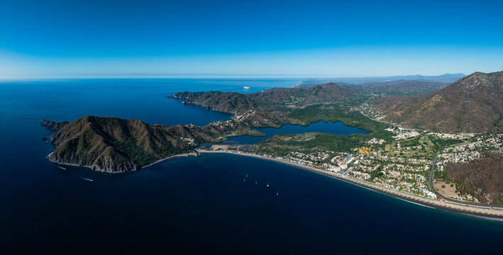 Wide aerial panoramic view of Playa de Oro and Juluapan peninsula with lagoon and Pacific Ocean in Manzanillo, Colima, Mexico