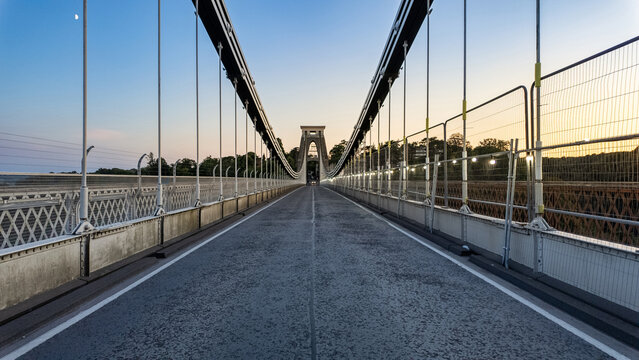 View of Clifton Suspension Bridge with its iconic stone tower and suspension cables under a clear twilight sky Bristol, United Kingdom.