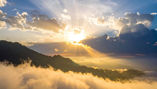 Sunbeams burst through clouds above misty mountain range at golden hour