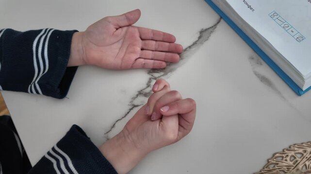 Little boy counting mathematical examples on fingers while bending one finger after another. Educational childhood activity and early learning concept in close-up.
