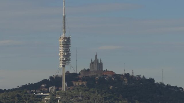 Scenic view of tibidabo mountain in barcelona with the sacred heart church and collserola tower as a sunbeam passes through the landscape creating a beautiful flare effect