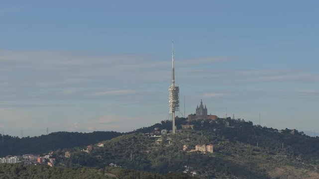 Scenic view of the torre de collserola and the temple of the sacred heart of jesus on the tibidabo mountain with shimmering heat waves rising from the landscape in barcelona