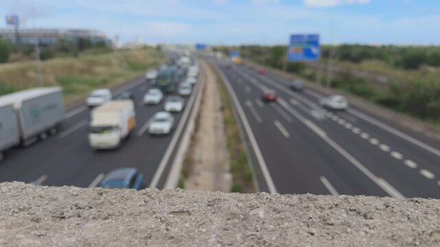 Highway traffic jam with cars and trucks driving from a concrete bridge view with a blurred background showing the concept of transportation, logistics and pollution