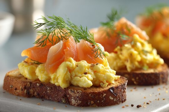 Toasted multigrain bread topped with creamy scrambled eggs, smoked salmon slices, and fresh dill herb garnish served as a gourmet breakfast appetizer