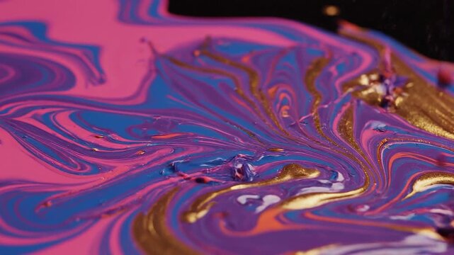 Close-up of vibrant colorful swirling paint with purple pink blue and gold abstract art patterns