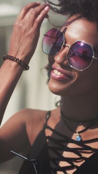 Bright confident portrait, Radiant lady sporting round shades and laceup attire at lively outdoor celebration